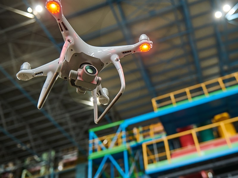 Inspeção por drone em uma instalação industrial, mostrando um drone em voo próximo a estruturas coloridas de metal.